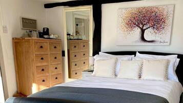 A bedroom with a bed, a wooden dresser, a chair, and a painting on the wall.