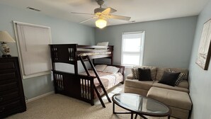 A compact living space with a bunk bed, a sofa, a glass coffee table, and a ceiling fan. - Waterfront 4 BR retreat at the sound side and only 100 steps to the ocean beach. (Emerald Isle)