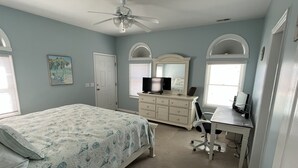A bedroom with a bed, dresser, desk, and ceiling fan. - Waterfront 4 BR retreat at the sound side and only 100 steps to the ocean beach. (Emerald Isle)