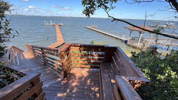 A wooden deck leading to a dock with a sign reading "Bluewater." - Waterfront 4 BR retreat at the sound side and only 100 steps to the ocean beach. (Emerald Isle)