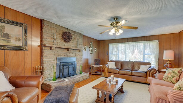 A living room with a fireplace, leather sofas, a wooden coffee table, and a ceiling fan. - Haysi Nature Getaway w/ Fire Pit & On-Site Creek! (Haysi)