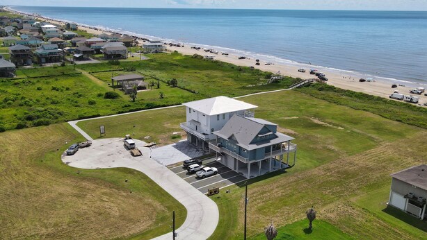 An aerial view of a coastal property with a large house featuring a spacious deck and a covered patio area. - Beachfront in Crystal Beach!  Beautiful views!  Game room! (Crystal Beach)