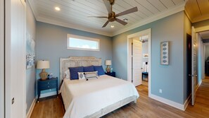 A bedroom with a bed, two bedside tables, a ceiling fan, a window, and a door leading to another room. - Beachfront in Crystal Beach! Beautiful views! Game room! (Crystal Beach)