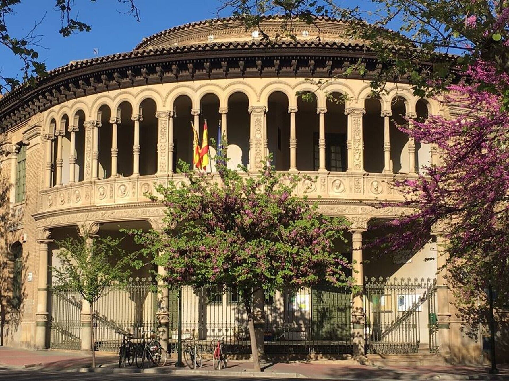 Um edifício histórico com um pátio central, colunas e uma bandeira.