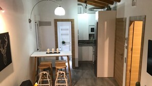 A compact living space with a dining area, kitchenette, and a door leading to another room. - FLATS 20 Ático · Check-in 24h NEW!! Increíble ático en el CENTRO 1000 Estrellas! (Zaragoza)