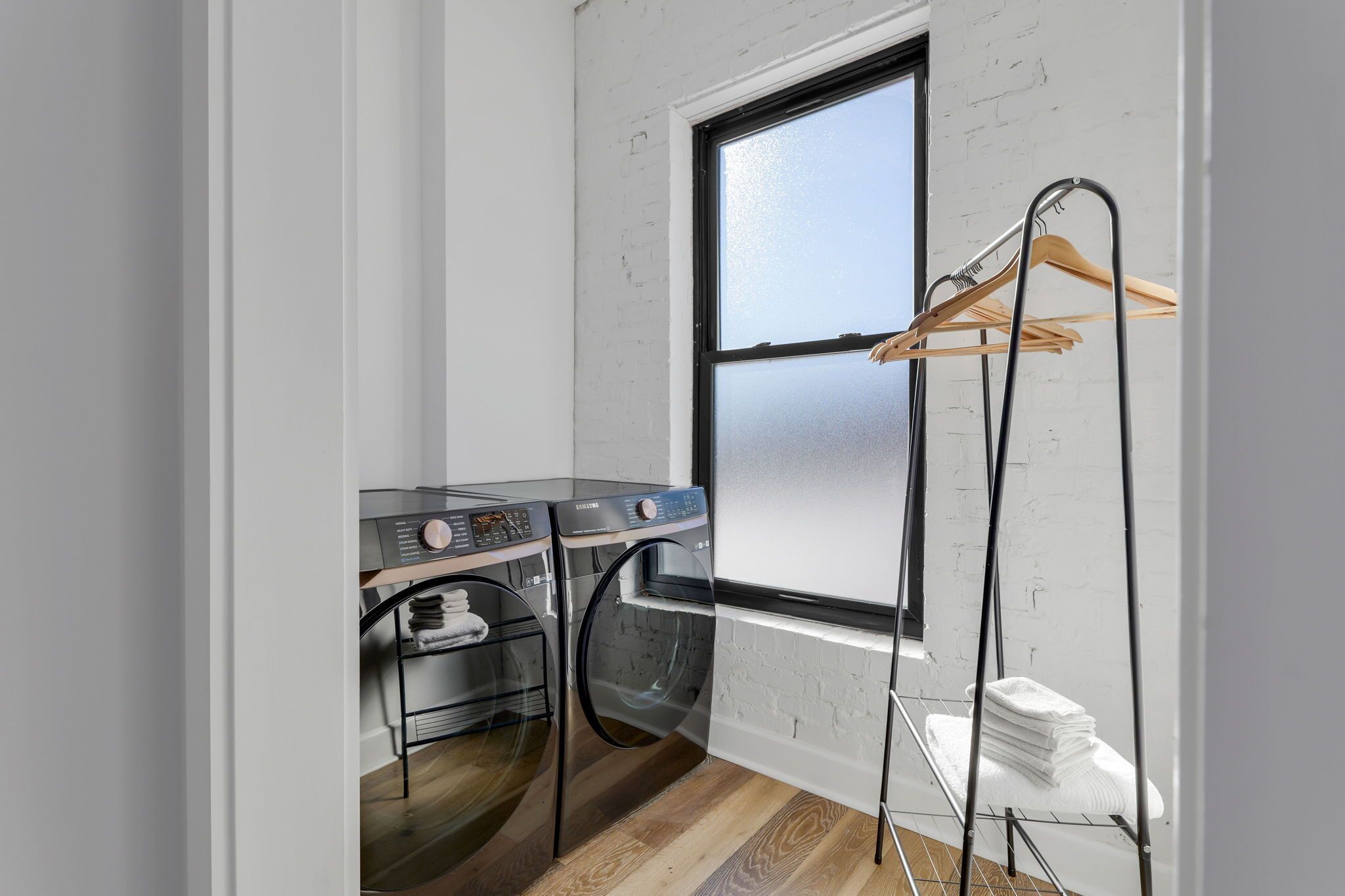 A laundry room with two washing machines and a drying rack.