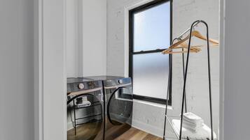 A laundry room with two washing machines and a drying rack.