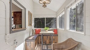 Une pièce chaleureuse avec un banc en bois, une chaise en osier et une table agrémentée d’une plante.