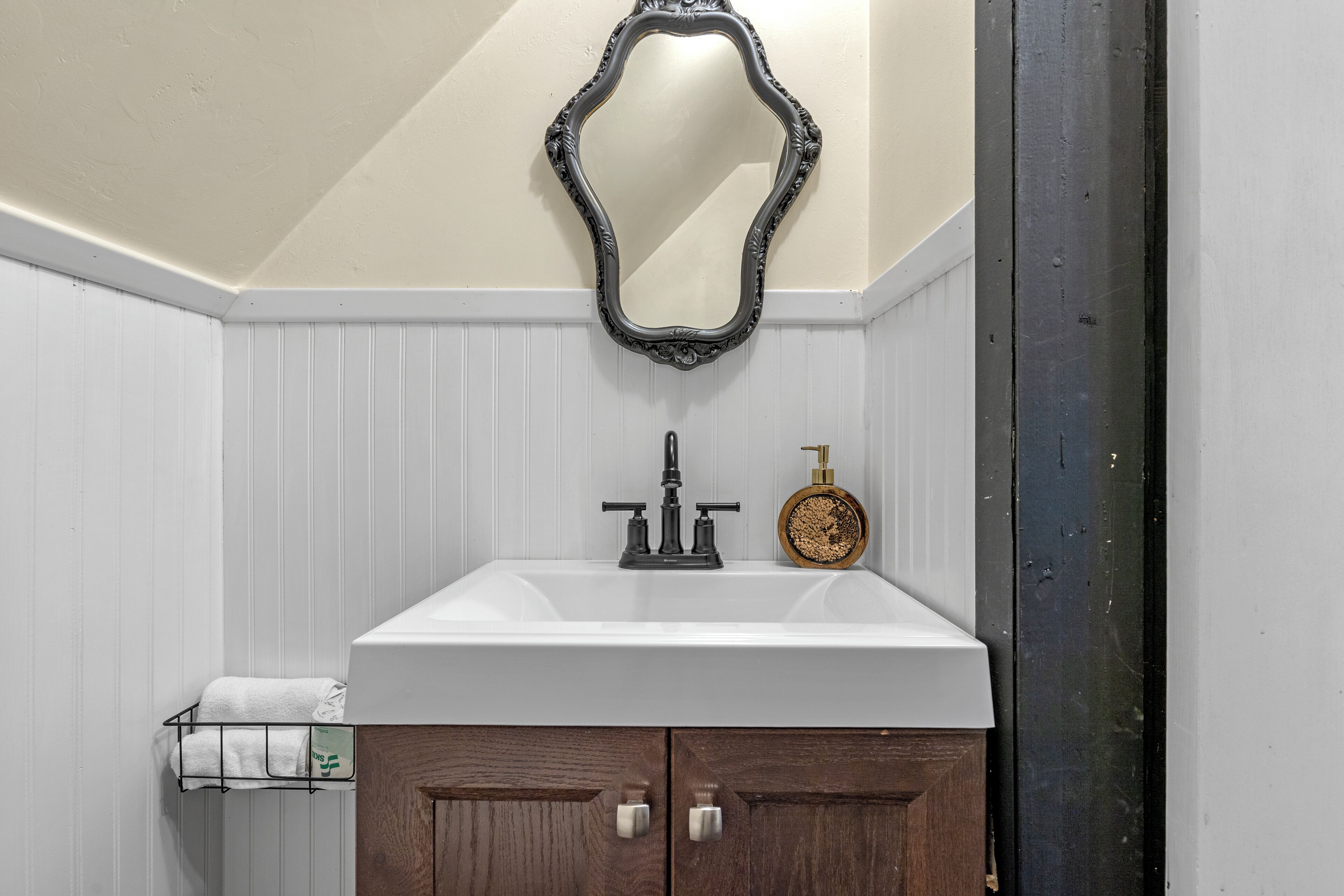 Une salle de bain avec un meuble-lavabo blanc, un miroir et un porte-serviettes.