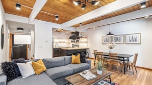 A modern living room with a grey sofa, wooden dining table, and a kitchen in the background. - Motherlode A5 (Breckenridge)