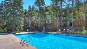 A swimming pool with a clear blue water, surrounded by lounge chairs and a wooden deck. - Motherlode A5 (Breckenridge)