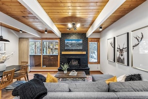 Un salon moderne doté d’une cheminée, d’un plafond en bois et de grandes fenêtres.