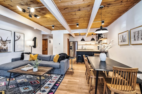 A modern living room with a sofa, coffee table, and dining area.