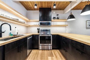 A modern kitchen with a built-in oven, a microwave, and a stainless steel range hood. - Motherlode A5 (Breckenridge)