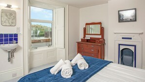 A bedroom with a bed, a dresser, a mirror, a fireplace, and a window with a view of the outdoors. - 5 bedroom accommodation in Stoke Gabriel, near Totnes (Stoke Gabriel, near Totnes)