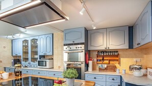 A modern kitchen with blue cabinets, a built-in oven, a microwave, and a wooden countertop. - 5 bedroom accommodation in Stoke Gabriel, near Totnes (Stoke Gabriel, near Totnes)