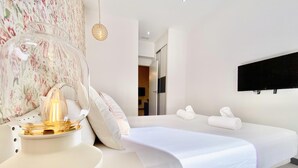 Ein modernes Hotelzimmer mit einem Bett, einem Nachttisch mit Lampe und einem an der Wand montierten Fernseher.