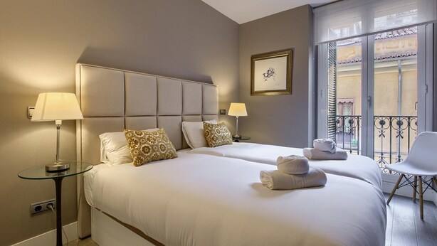 Ein Hotelzimmer mit zwei Betten, einem Glastisch und einem Balkon mit einem Stuhl.