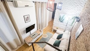 Uma sala de estar moderna com uma televisão de tela plana, um sofá, uma mesa de centro e uma escada.