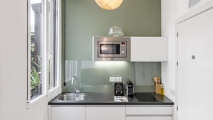 A modern kitchen with a built-in microwave, a coffee maker, and a sink. - Home Suite Home I - Studio apartment with terrace in the center (Madrid)