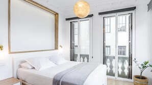 A modern bedroom with a large bed, a wooden nightstand, a mirror, and a hanging light fixture. - Home Suite Home I - Studio apartment with terrace in the center (Madrid)