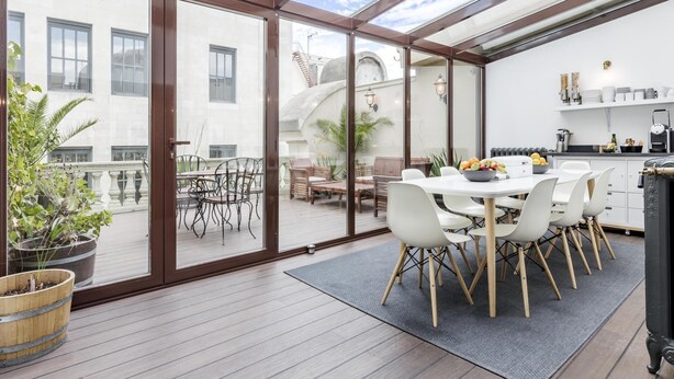 A spacious balcony with a dining area, a kitchen, and a view of the cityscape. - Home Suite Home I - Studio apartment with terrace in the center (Madrid)