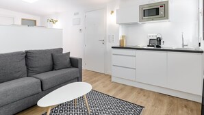 A modern living room with a grey sofa, a white coffee table, and a patterned rug. - Home Suite Home II - Studio apartment with large shared terrace (Madrid)