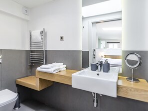 Ein modernes Badezimmer mit einem weißen Waschbecken, einem Spiegel und einem Handtuchhalter.