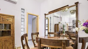Un coin repas avec une table et des chaises en bois, un grand miroir et un meuble avec des portes en verre.