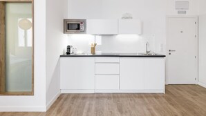 A modern kitchen with white cabinetry, a microwave, and a sink. - Home Suite Home III - Studio apartment with large shared terrace (Madrid)