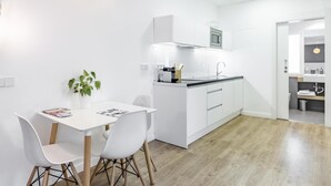 A modern kitchen with white cabinetry, a central island, and a dining area with a table and chairs. - Home Suite Home IV - Studio apartment with large shared terrace (Madrid)