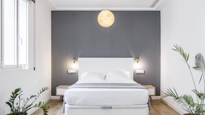 A modern bedroom with a large bed, bedside tables, a hanging light fixture, and two potted plants. - Home Suite Home IV - Studio apartment with large shared terrace (Madrid)