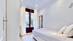 A modern bedroom with a bed, a door, and a view of the outside balcony. - Puerta de Toledo VII - 2-Bedroom Apartment (Madrid)