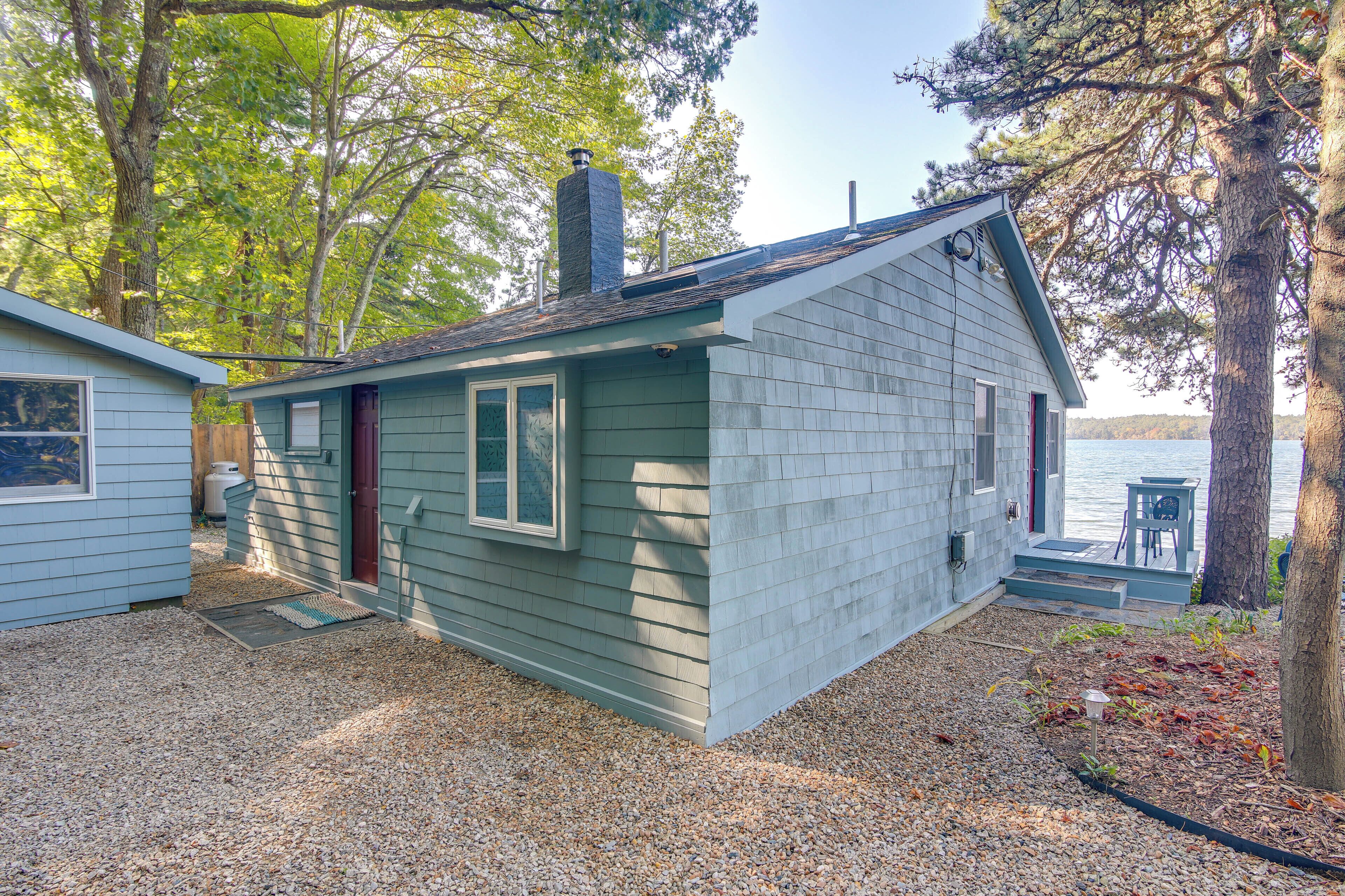 Une petite cabane avec une cheminée, une porte et une fenêtre.