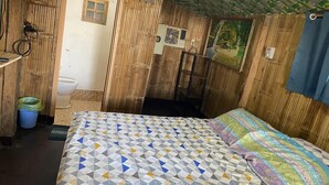 A room with a bed, a wooden wall, a window, a door, and a bathroom.