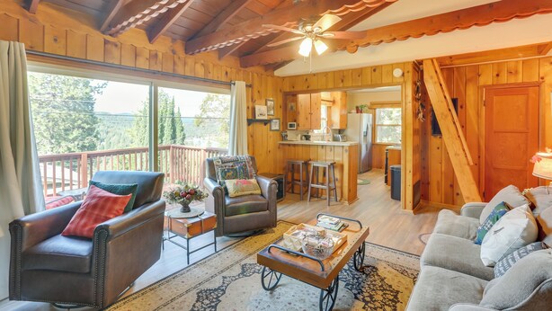 Un intérieur de chalet chaleureux avec un plafond en bois, un coin repas et une vue sur l’extérieur.