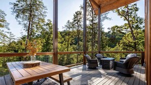 Een houten terras met een tafel en stoelen, omringd door bomen.