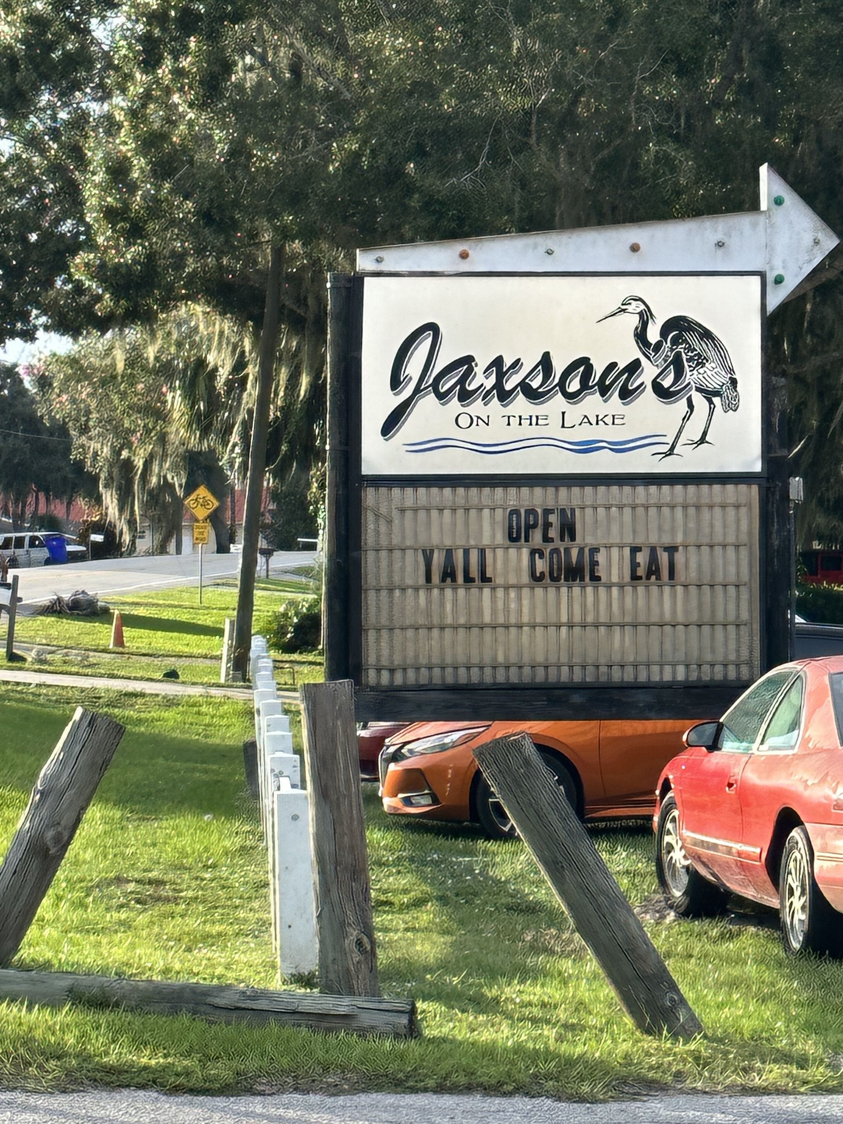 A restaurant sign with a bird logo and the text "Jaxson's On the Lake" and "OPEN YALL COME EAT".