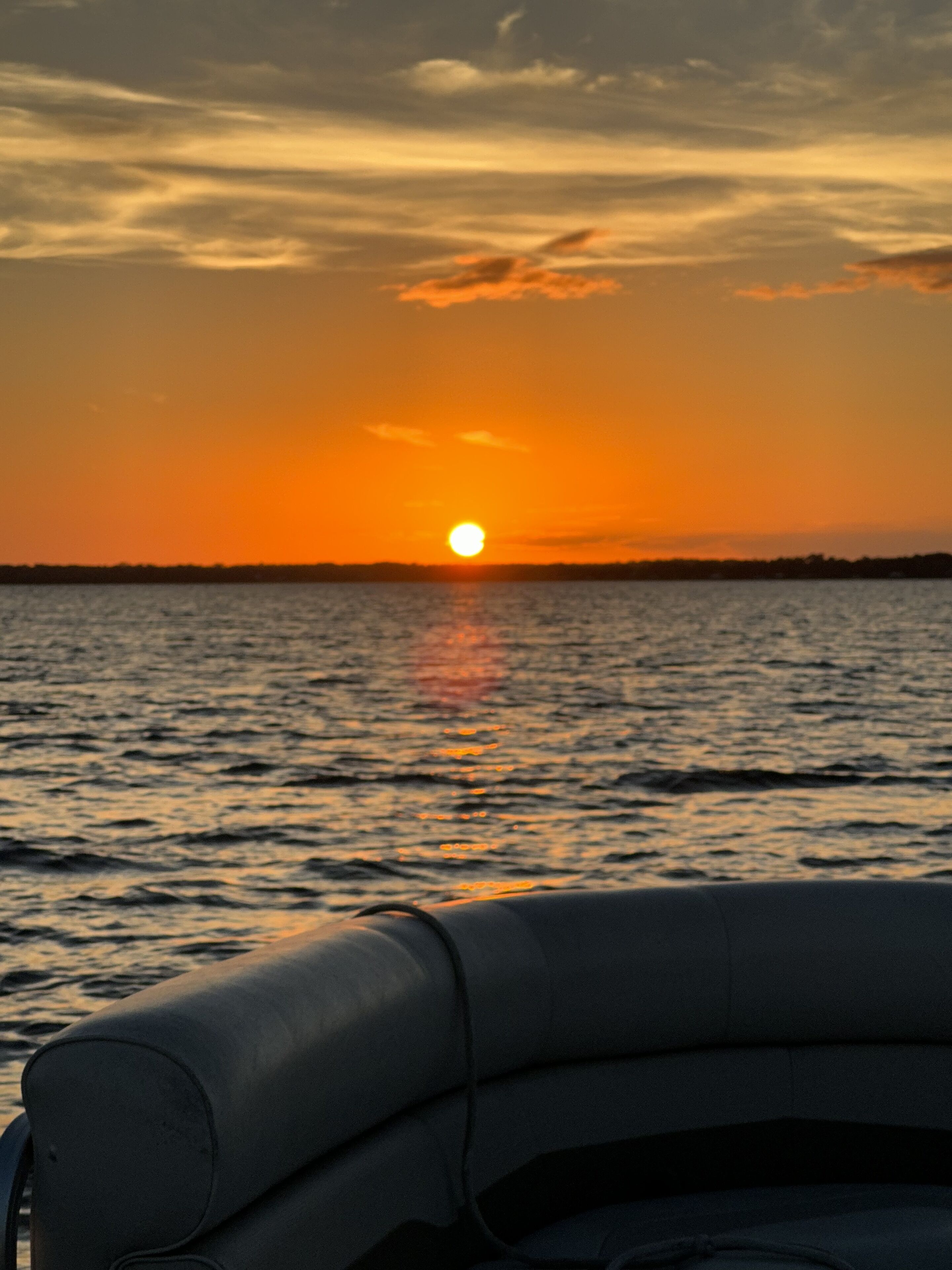 A sunset over a body of water with a boat in the foreground.