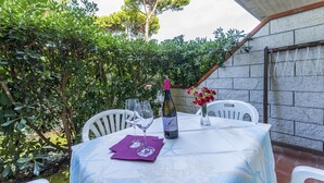 An outdoor dining area with a table set for two, surrounded by lush greenery and a stone wall. - Residence in Giannella with 0 bedrooms sleeps 4 (Giannella)