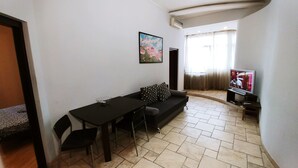 A compact living space with a dining area, a sofa, a TV, and a painting on the wall. -  Studio. 5 Lesi Urainky blvd. Near Parus, Gulliver  (Passau)
