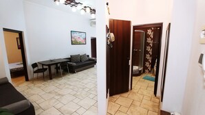 A room with a dining table, chairs, a sofa, and a shower area with a glass door. -  Studio. 5 Lesi Urainky blvd. Near Parus, Gulliver  (Passau)