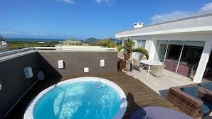 En tagterrasse med swimmingpool, udendørs møbler og havudsigt.