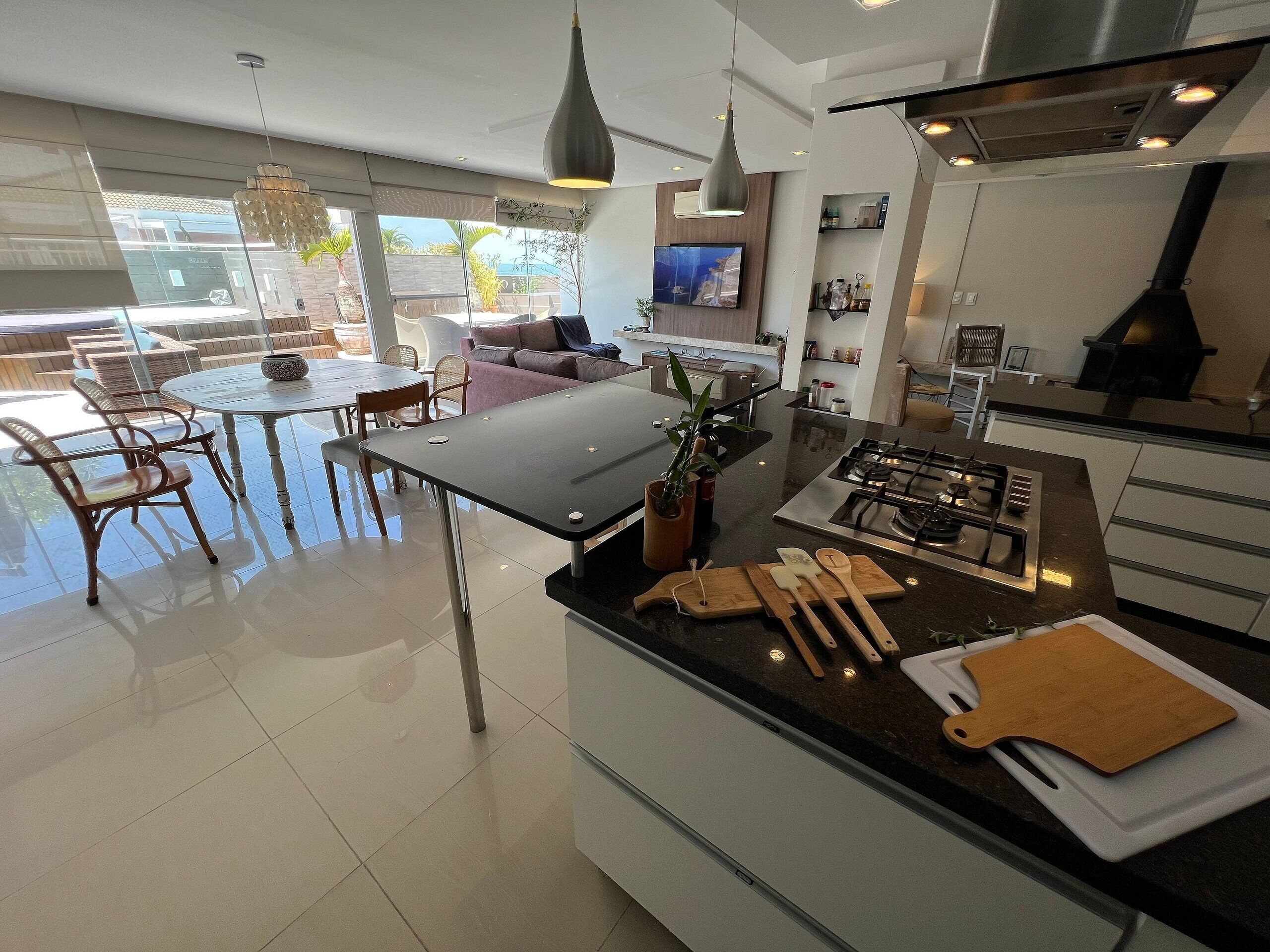 Uma cozinha moderna com uma ilha central, eletrodomésticos de aço inoxidável e uma área de jantar com móveis de vime.