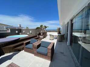 Une terrasse sur le toit avec une piscine, des sièges extérieurs et une vue sur l’océan.