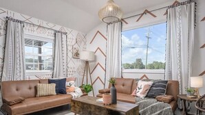 A modern living room with a brown leather sofa, a wooden coffee table, and patterned curtains. - Perfect cozy bungalow for a weekend away or a week fishing🐟 (Sale Creek)