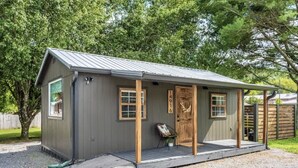 A small, single-story building with a metal roof, wooden door, and windows. - Perfect cozy bungalow for a weekend away or a week fishing🐟 (Sale Creek)