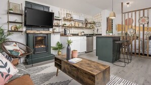 A modern kitchen with a flat-screen TV, wooden shelves, and a fireplace. - Perfect cozy bungalow for a weekend away or a week fishing🐟 (Sale Creek)