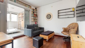 A modern living room with a sofa, a coffee table, a chair, a bookshelf, a dartboard, and a sliding door leading to a balcony. - GuestHost - APT with large terrace - Calvairate neighborhood (Milano)
