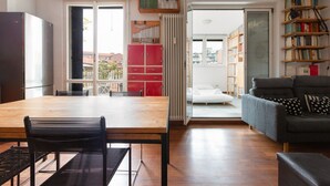 A modern living space with a wooden dining table, black chairs, a grey sofa, and a red cabinet. - GuestHost - APT with large terrace - Calvairate neighborhood (Milano)